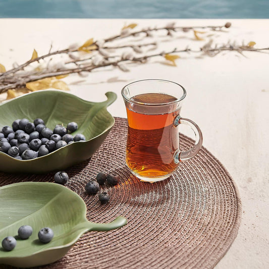 Glass of tea with a bowl of blueberries on a woven mat